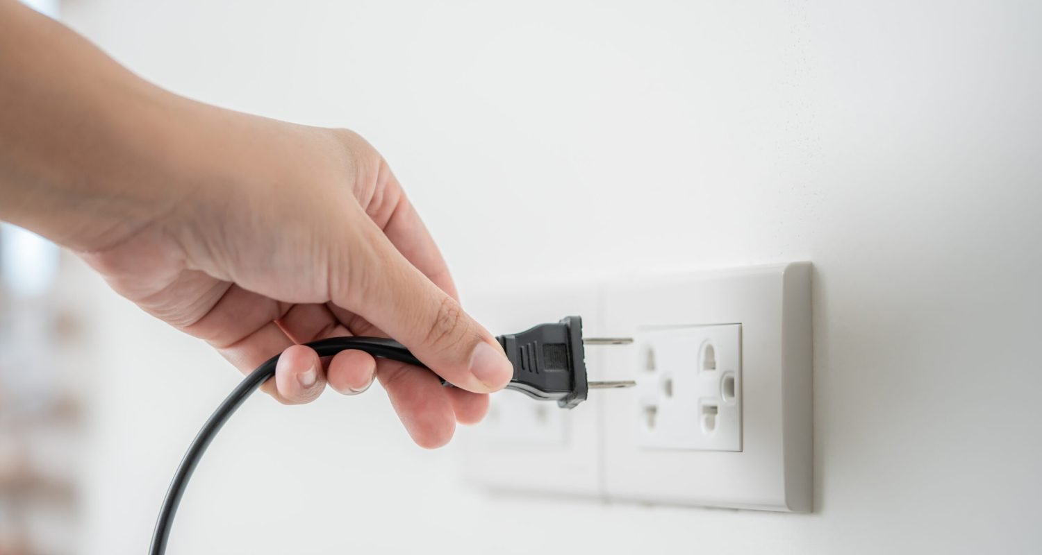 Human hand put in or out electric plug in the socket to connect the devices. Household technology in use of human hand. Using of electric plug concept of safety, or environmental conservation.