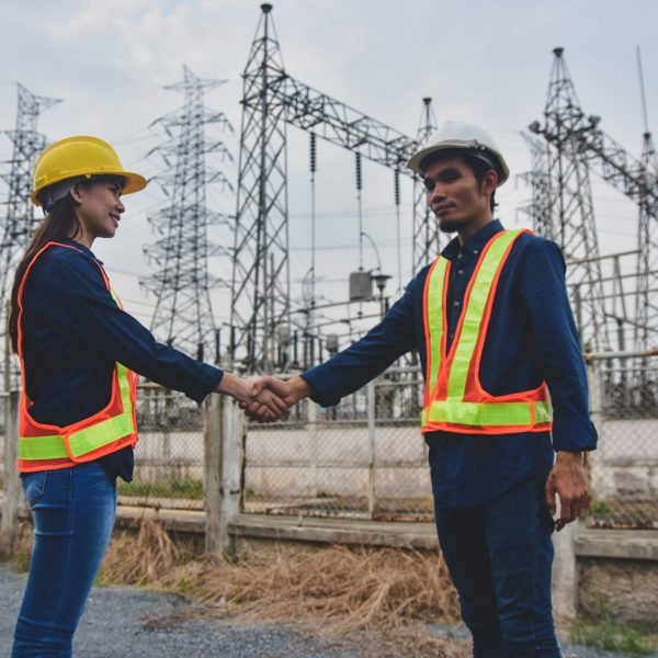 Man and Women Engineering standing shake hand finished project at power plant  electrical system background