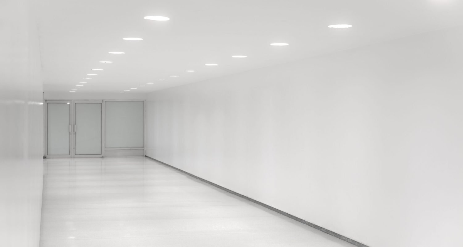 A white lightful corrdior with white door and ceiling white lamps